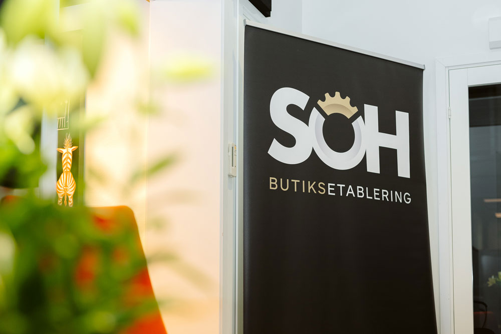 Bo och Martina från SOH Butiksetablering sitter i en grå soffa